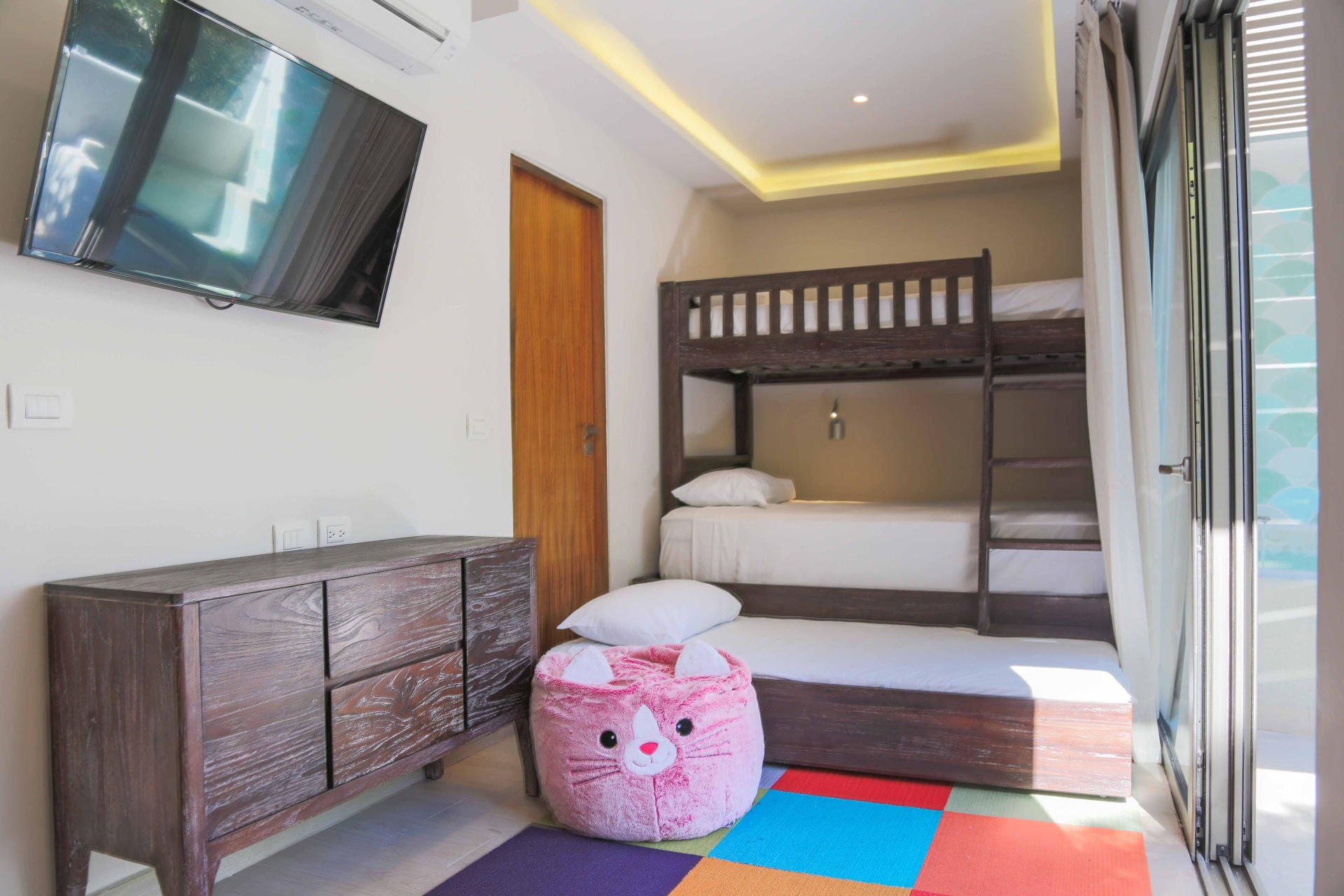 Habitación tipo infantil, con literas de madera oscura, juguetes de ocio infantil y televisor