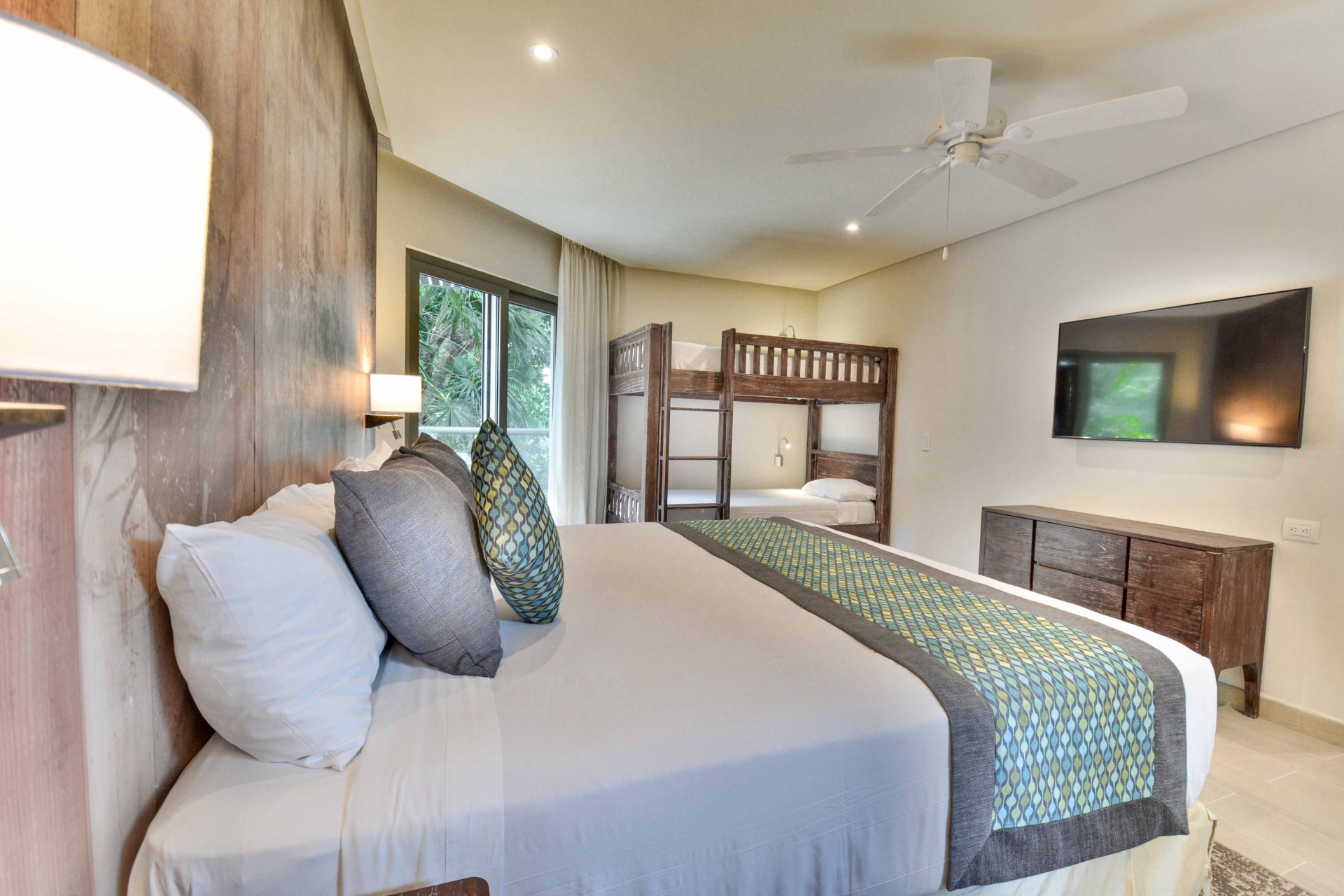 habitación con cama doble grande y literas al fondo.